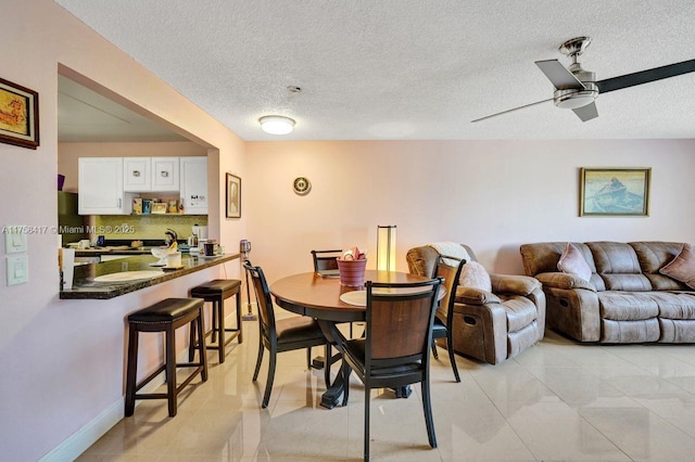 dining area with light tile patterned floors, a textured ceiling, and a ceiling fan