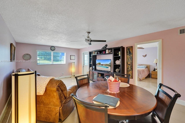 dining room featuring visible vents, baseboards, a textured ceiling, and ceiling fan