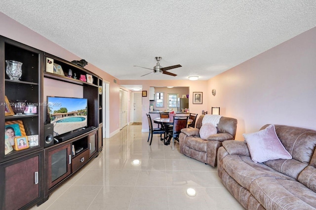 living area with light tile patterned floors, baseboards, a textured ceiling, and a ceiling fan