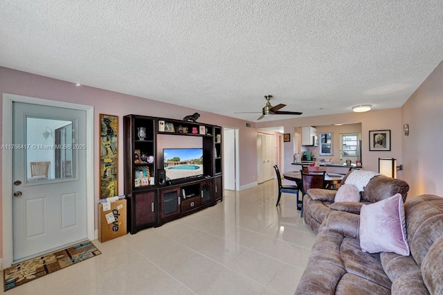 living area with light tile patterned flooring, a ceiling fan, and a textured ceiling