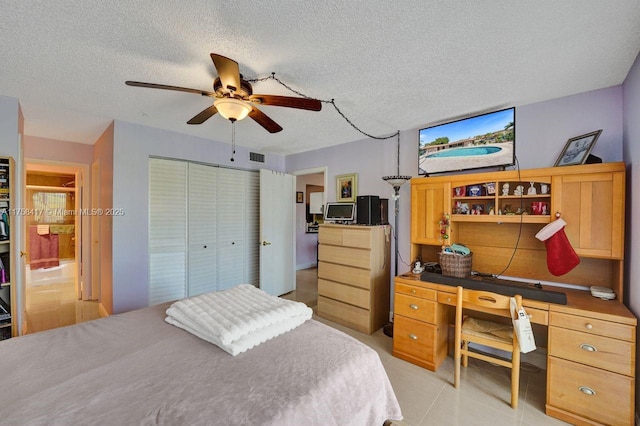 bedroom with visible vents, a textured ceiling, a closet, light tile patterned flooring, and ceiling fan