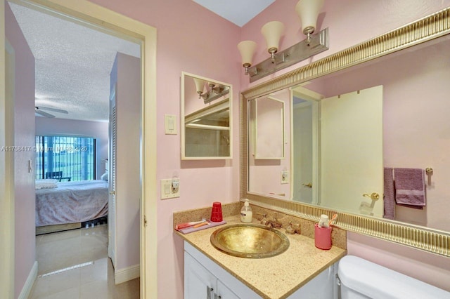 bathroom with toilet, ensuite bathroom, a textured ceiling, tile patterned flooring, and vanity