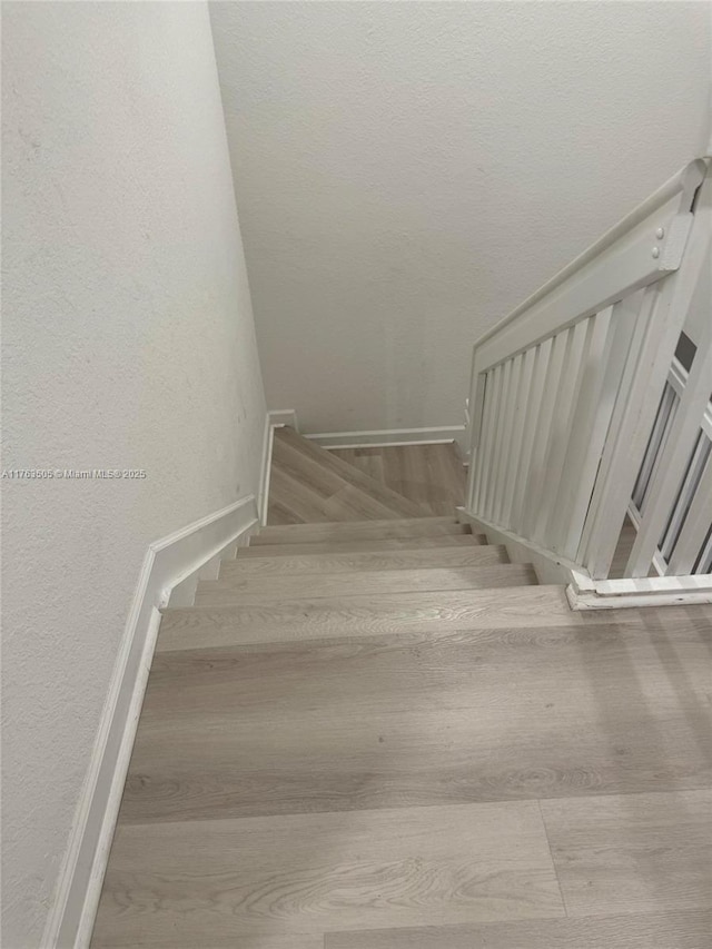 staircase with a textured wall and wood finished floors