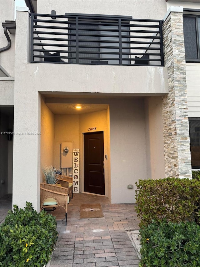 entrance to property with stucco siding and a balcony