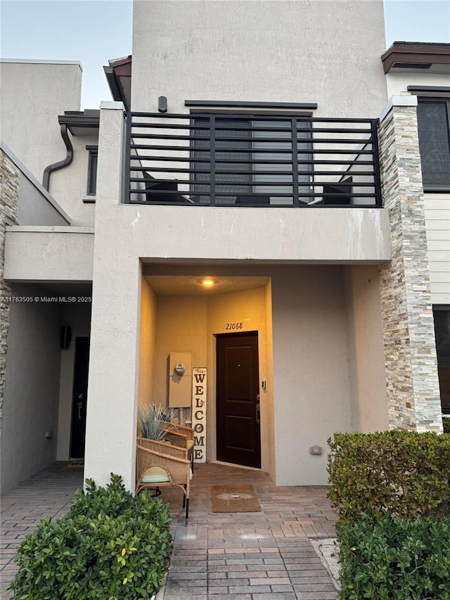 entrance to property featuring a balcony and stucco siding