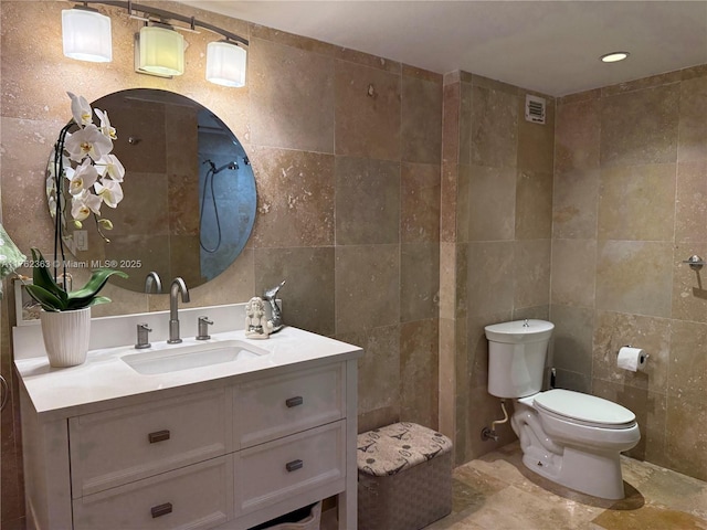 bathroom with vanity, tile walls, toilet, and visible vents