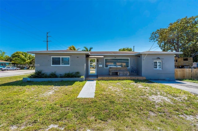 ranch-style house with a front yard, fence, and stucco siding