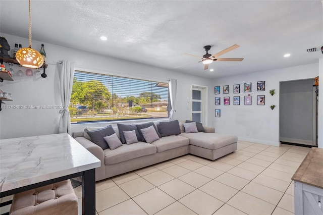 living area featuring light tile patterned floors, a ceiling fan, visible vents, baseboards, and recessed lighting