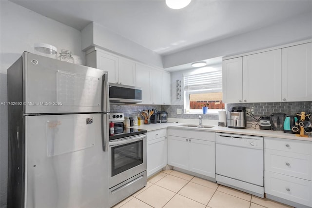 kitchen featuring tasteful backsplash, light countertops, appliances with stainless steel finishes, white cabinets, and a sink