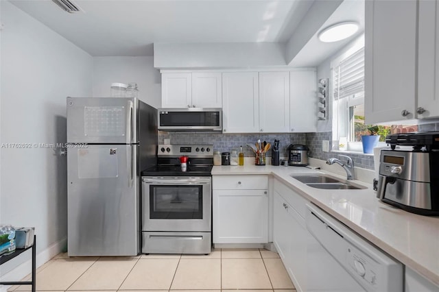 kitchen featuring a sink, tasteful backsplash, stainless steel appliances, white cabinets, and light tile patterned floors