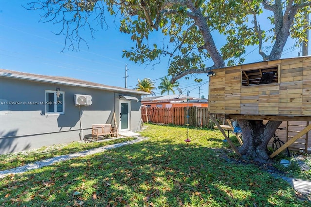 view of yard with a wall mounted air conditioner, an outdoor structure, and fence