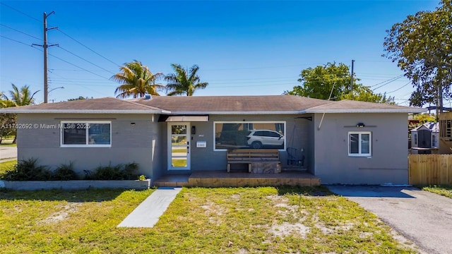 view of front of house with stucco siding, a front yard, and fence