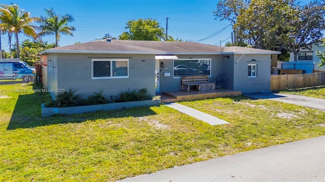 view of front of property with a front yard, fence, and stucco siding