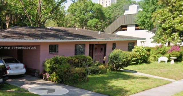 view of front of home featuring an attached carport, a front yard, stucco siding, a chimney, and driveway