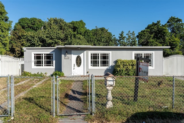 view of front of property featuring a front lawn, a gate, a fenced front yard, and stucco siding