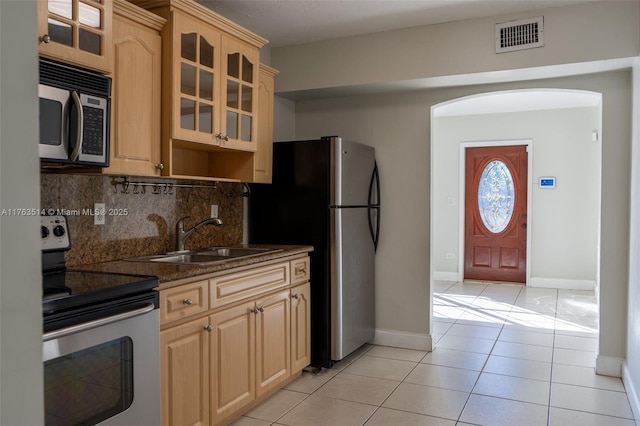 kitchen featuring visible vents, a sink, backsplash, appliances with stainless steel finishes, and light tile patterned floors