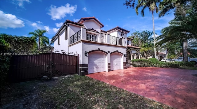 view of side of home featuring a balcony, a garage, driveway, and stucco siding