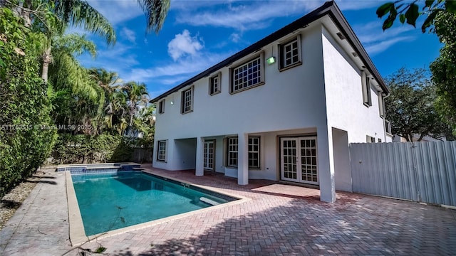 rear view of house with a patio area, fence, french doors, and stucco siding