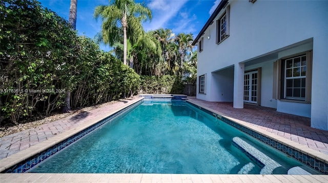 view of pool with a pool with connected hot tub, a patio, and fence