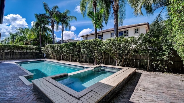 view of swimming pool featuring a patio, a fenced backyard, and a pool with connected hot tub