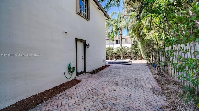 view of property exterior featuring stucco siding, a patio, and fence