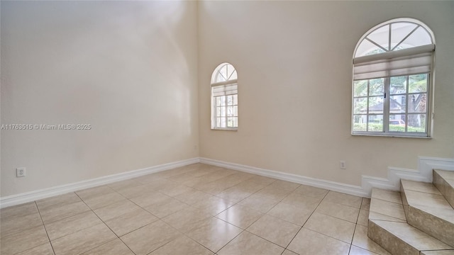 spare room with light tile patterned floors, baseboards, and stairs