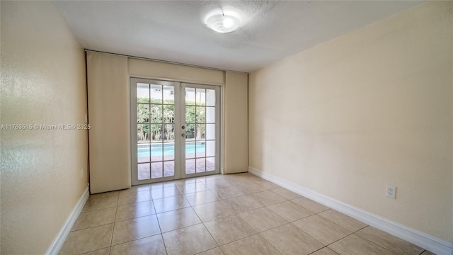 spare room with light tile patterned flooring, french doors, and baseboards