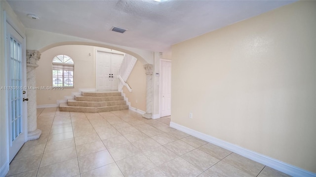 entrance foyer featuring arched walkways, visible vents, baseboards, and light tile patterned flooring