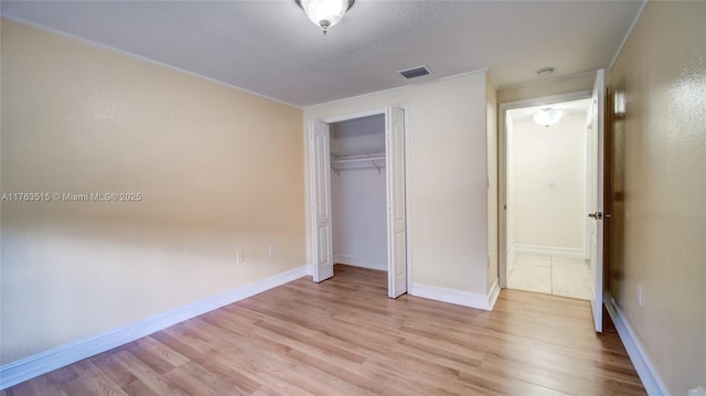 unfurnished bedroom featuring baseboards, visible vents, a closet, and light wood-type flooring