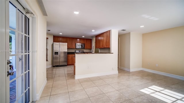 kitchen featuring dark countertops, baseboards, light tile patterned floors, recessed lighting, and appliances with stainless steel finishes