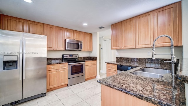 kitchen featuring visible vents, a sink, dark stone counters, appliances with stainless steel finishes, and light tile patterned flooring