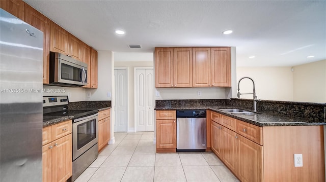 kitchen featuring visible vents, a sink, appliances with stainless steel finishes, a peninsula, and light tile patterned floors