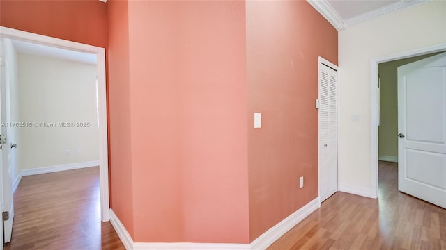 hall with baseboards, light wood-style floors, and ornamental molding