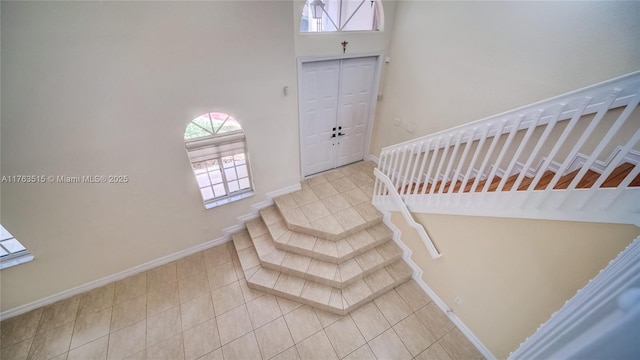 entrance foyer with baseboards, stairs, and tile patterned flooring