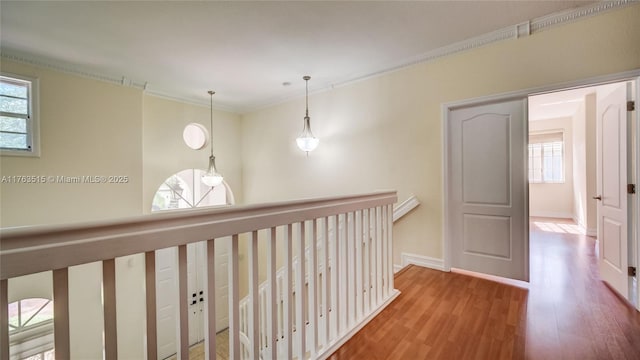 hall featuring an upstairs landing, ornamental molding, baseboards, and wood finished floors