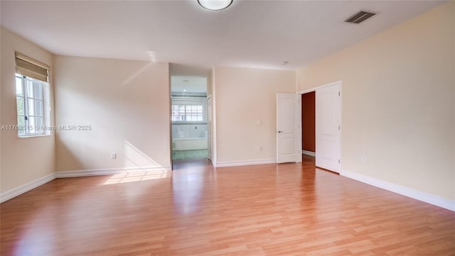 unfurnished room with light wood finished floors, visible vents, and baseboards