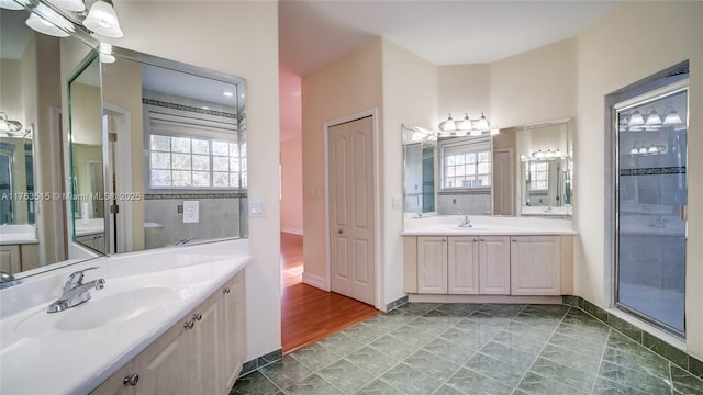 bathroom with a sink, plenty of natural light, and two vanities