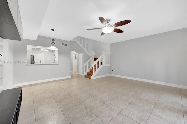 unfurnished living room featuring visible vents, baseboards, stairs, light tile patterned flooring, and a ceiling fan