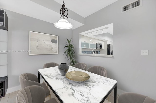 dining room featuring light tile patterned floors, visible vents, baseboards, and rail lighting