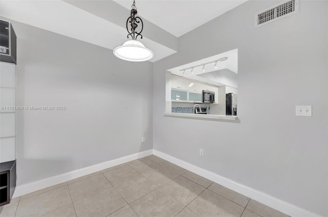 unfurnished dining area featuring light tile patterned floors, visible vents, baseboards, and rail lighting