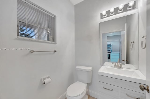 half bath with baseboards, toilet, and vanity