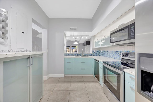 kitchen featuring visible vents, light countertops, decorative backsplash, appliances with stainless steel finishes, and a sink