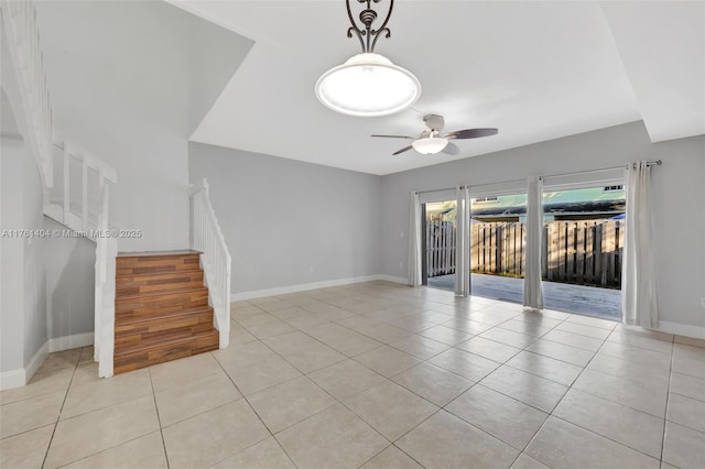 unfurnished living room featuring light tile patterned flooring, baseboards, stairs, and a ceiling fan