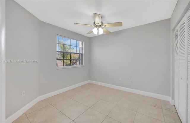 spare room featuring light tile patterned floors, baseboards, and ceiling fan