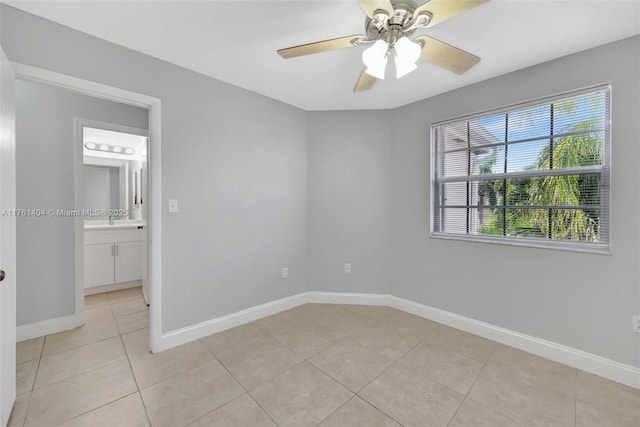 empty room with light tile patterned flooring, a ceiling fan, and baseboards