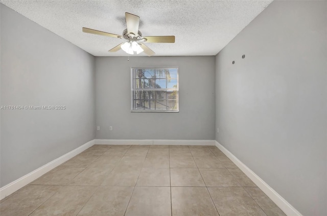 spare room with light tile patterned flooring, a ceiling fan, baseboards, and a textured ceiling