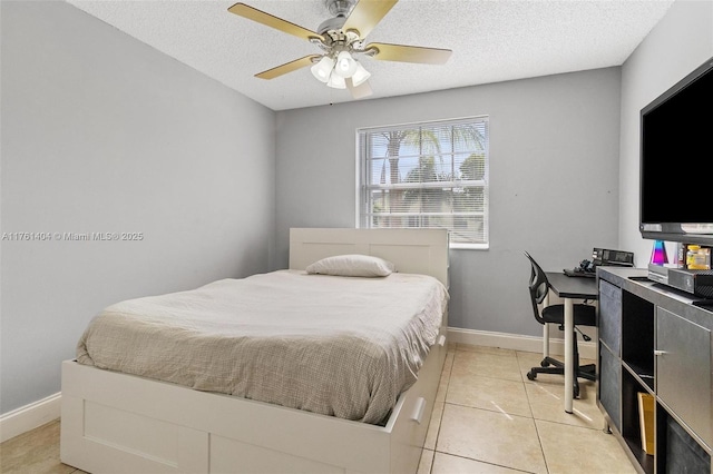 bedroom featuring light tile patterned floors, a ceiling fan, baseboards, and a textured ceiling