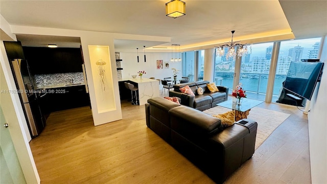 living area with a chandelier, floor to ceiling windows, and light wood-style flooring