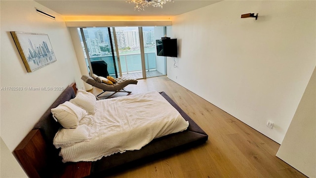 bedroom featuring an inviting chandelier, light wood-style flooring, and access to outside