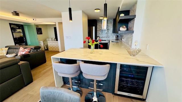 kitchen with open shelves, light stone counters, wine cooler, light wood finished floors, and decorative backsplash